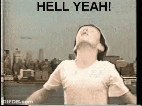 Man With Arms Outstretched In Front Of City Saying Hell Yeah GIF