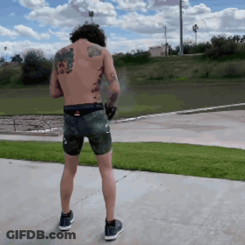 Man With Back Tattoo Standing On Sidewalk GIF