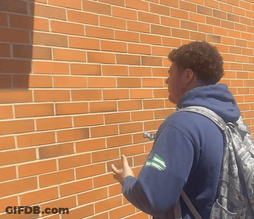 Man With Backpack By Brick Wall GIF
