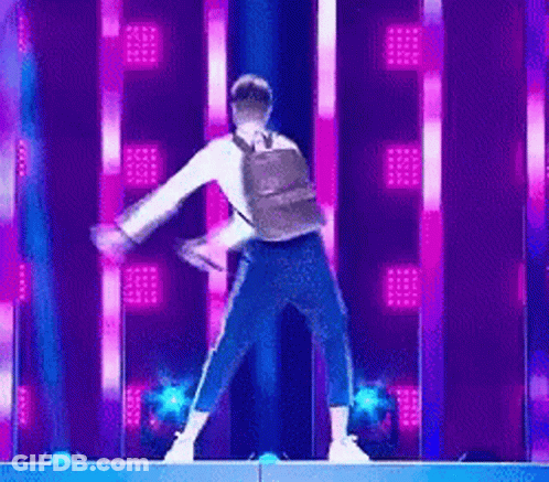 Man With Backpack Dancing On Stage With Purple Lights GIF
