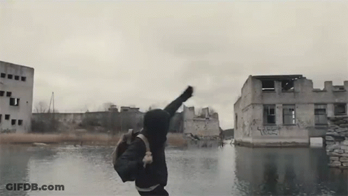 Man With Backpack Jumping Over Water By Graffiti Building GIF