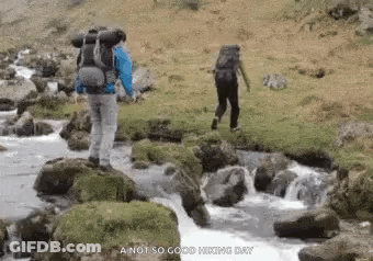 Man With Backpack Walking Across River GIF
