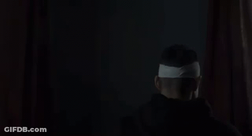 Man With Bandage On Head Smiling In Dark GIF
