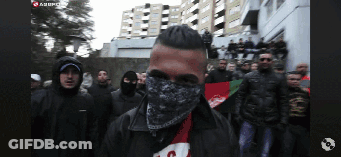 Man With Bandana Stands In Front Of Group GIF