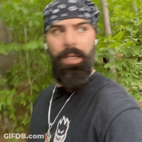 Man With Beard And Bandana Walking Through Woods GIF