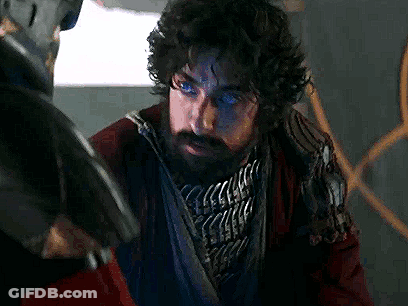 Man With Beard And Blue Eyes Next To Man Holding Gun GIF