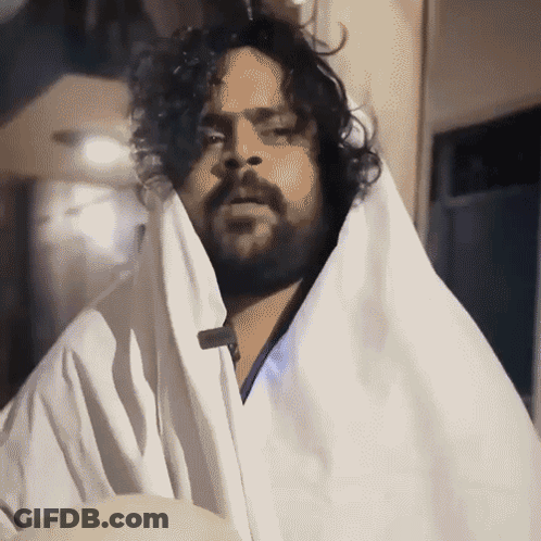 Man With Beard And Curly Hair In White Blanket GIF