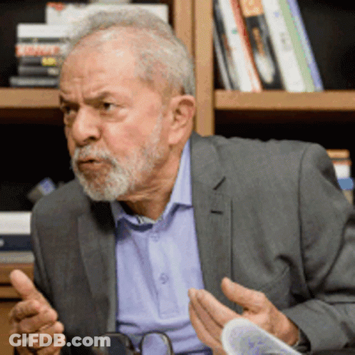 Man With Beard And Glasses Sitting In Front Of Bookshelf Talking GIF