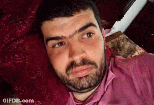 Man With Beard And Pink Shirt Lying On Bed GIF