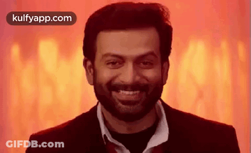 Man With Beard And Suit Smiling In Front Of Red Background GIF