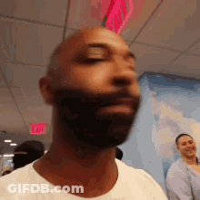 Man With Beard And White Shirt In Front Of Exit Sign GIF