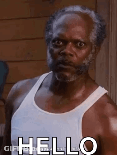 Man With Beard And White Tank Top In Front Of Wooden Wall GIF