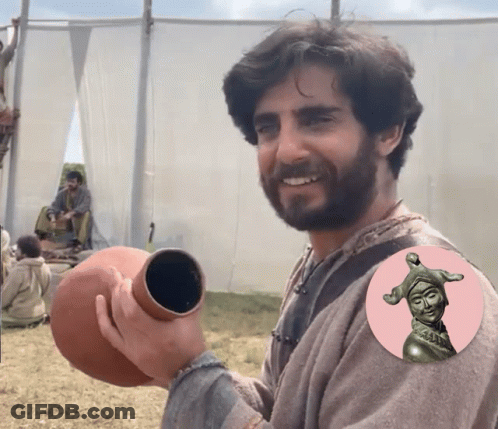 Man With Beard Holding Vase With Statue Of Jester GIF