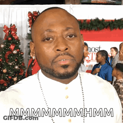 Man With Beard In Front Of Christmas Tree And Most Wanted Sign GIF