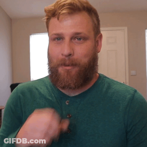 Man With Beard In Green Shirt Looks At Camera GIF