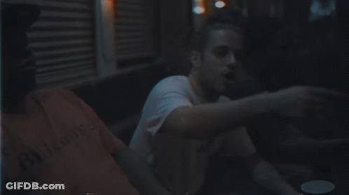 Man With Beard In White Shirt Sitting In Dark Room GIF