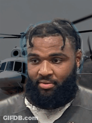 Man With Beard Looking At Camera With Helicopter Background GIF