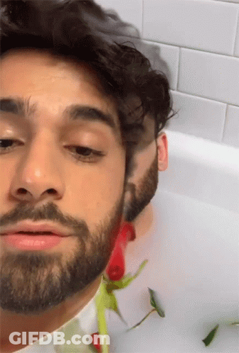Man With Beard Lying In Bathtub With Rose GIF