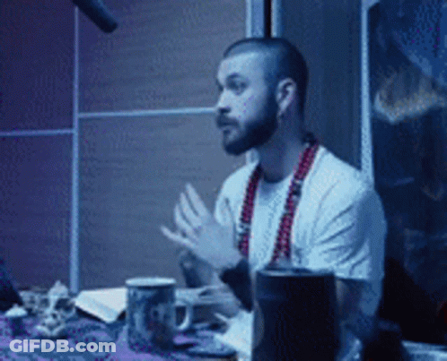 Man With Beard Sitting At Table With Microphone GIF