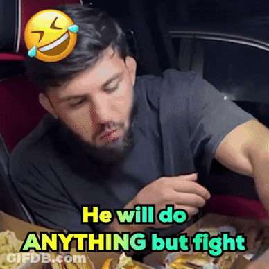 Man With Beard Sitting At Table With Smiley Face Saying He Will Do Anything But Fight GIF