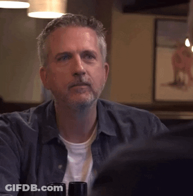 Man With Beard Sitting At Table With Wine Bottles GIF