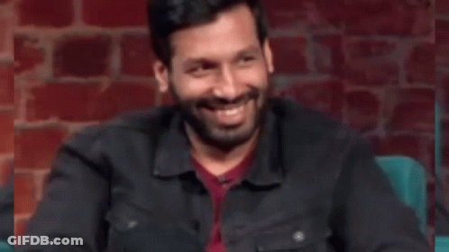 Man With Beard Sitting In Front Of Brick Wall Hand On Chest GIF