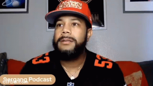 Man With Beard Sitting On Couch In Hat And Jersey GIF