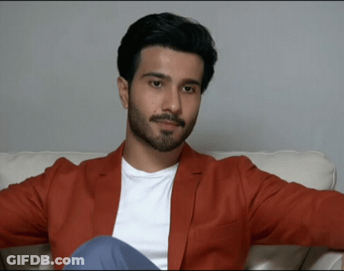 Man With Beard Sitting On Couch In Red Jacket GIF