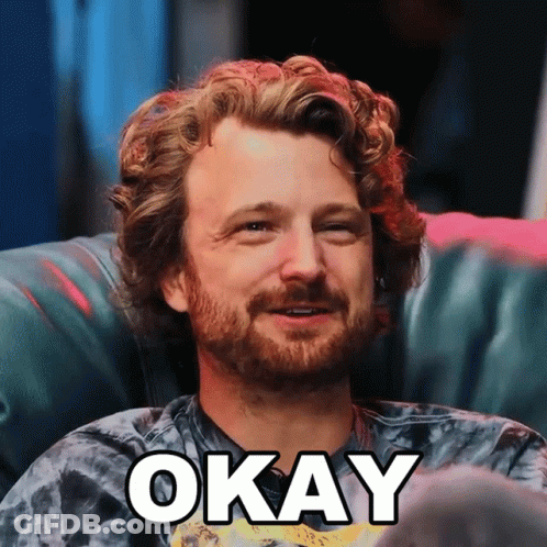 Man With Beard Sitting On Couch With Word Okay Above GIF