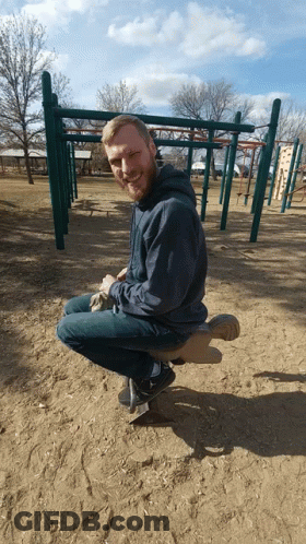 Man With Beard Sitting On Seesaw At Playground GIF
