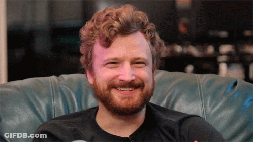 Man With Beard Smiling Sitting On Blue Leather Couch GIF