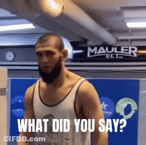 Man With Beard Standing In Front Of Mauler Bet Sign GIF