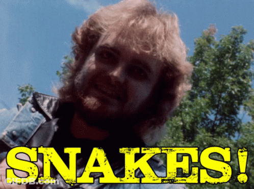 Man With Beard Standing In Front Of Snakes Sign GIF