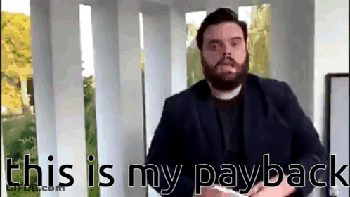 Man With Beard Standing In Front Of This Is My Payback Sign GIF