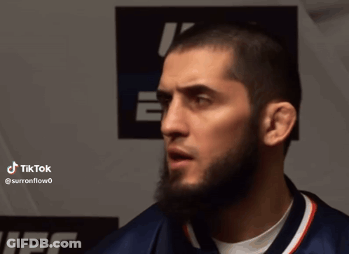 Man With Beard Standing In Front Of Tik Tok Sign GIF