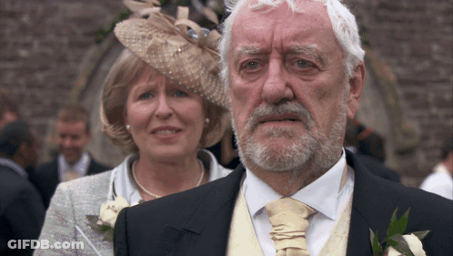 Man With Beard Standing Next To Woman In Hat GIF