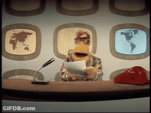 Man With Beard Standing On Stage In Front Of TV Logo GIF