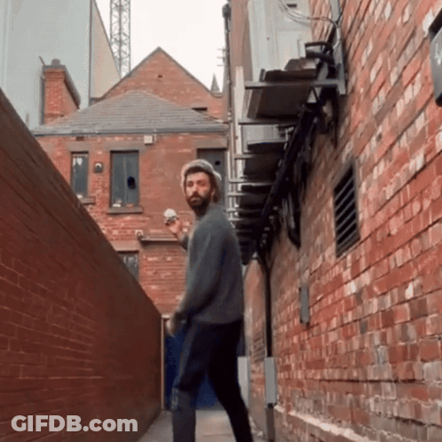 Man With Beard Walking Down Alleyway GIF