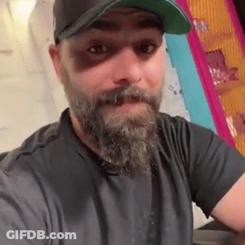 Man With Beard Wearing Baseball Cap And Black Shirt GIF