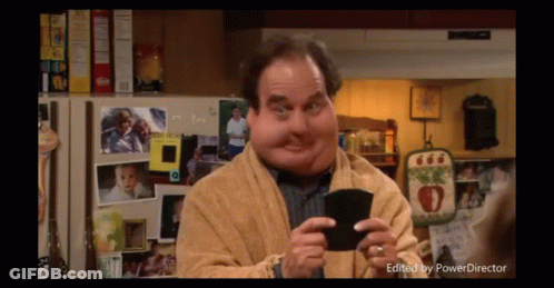 Man With Big Face Holding Wallet In Front Of Refrigerator With Pictures GIF