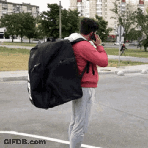 Man With Black Bag Talking On Phone GIF