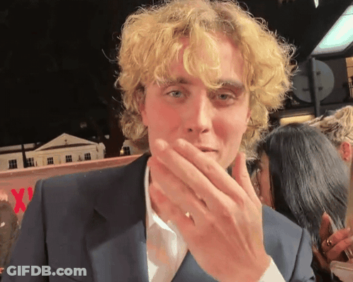 Man With Blonde Curly Hair Covering Mouth GIF