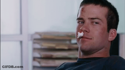 Man With Bloody Nose Sitting In Front Of Books GIF