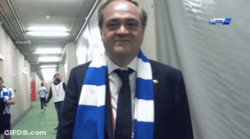 Man With Blue And White Scarf In Hallway RS Sign GIF
