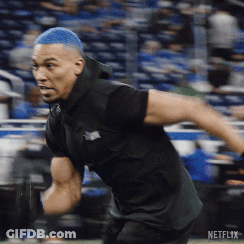 Man With Blue Hair Running In Front Of Netflix Logo GIF