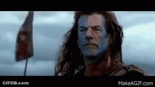 Man With Blue Paint On Face And Flag In Field GIF