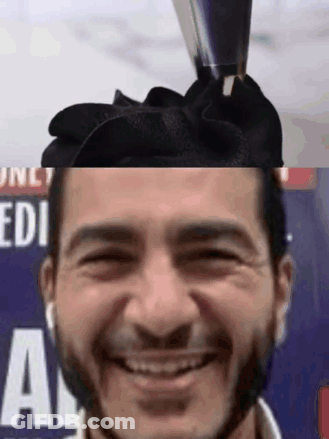 Man With Bow On Head Smiling In Front Of Edi Sign GIF