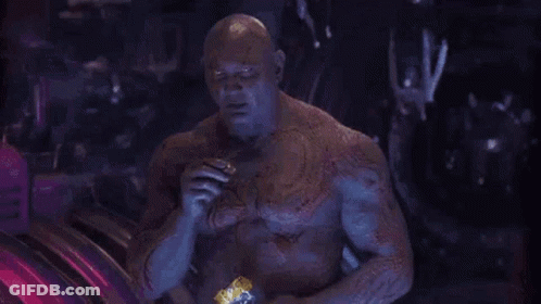 Man With Chest Tattoo Eating Snack In Dark Room GIF