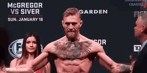 Man With Chest Tattoo In Front Of McGregor Vs Silver Sign GIF