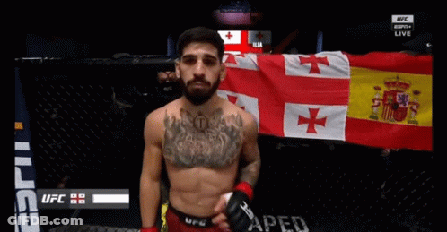 Man With Chest Tattoo In Front Of UFC Banner GIF